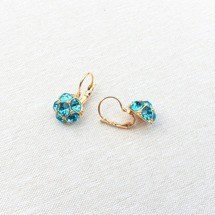 Gold earrings with blue gemstones on a white background