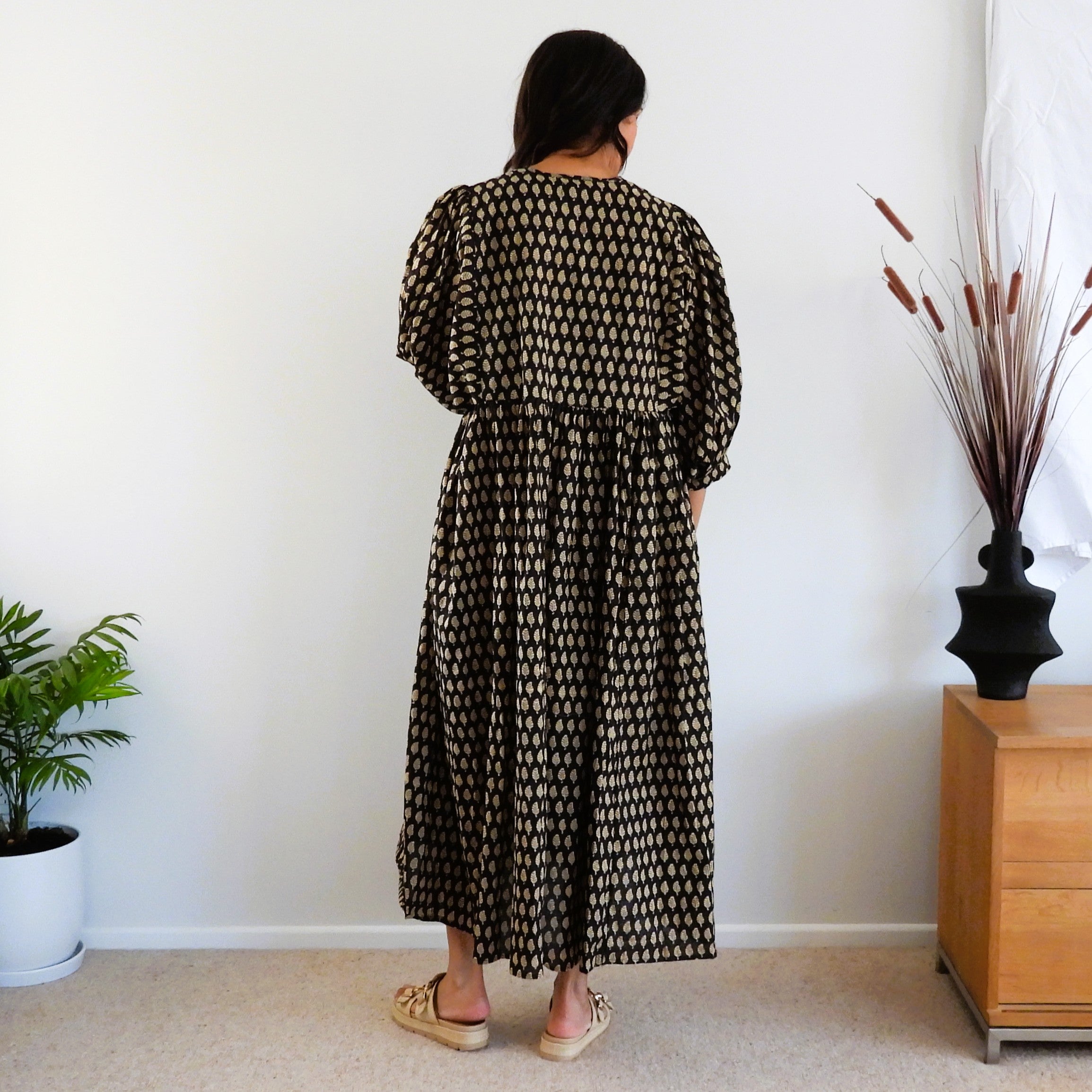 Back of woman's black and gold boho dress.